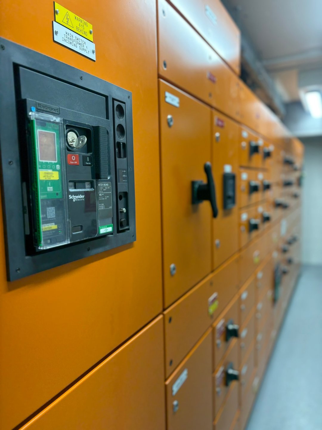 Main switch on an orange commercial switchboard with rows of distribution boards