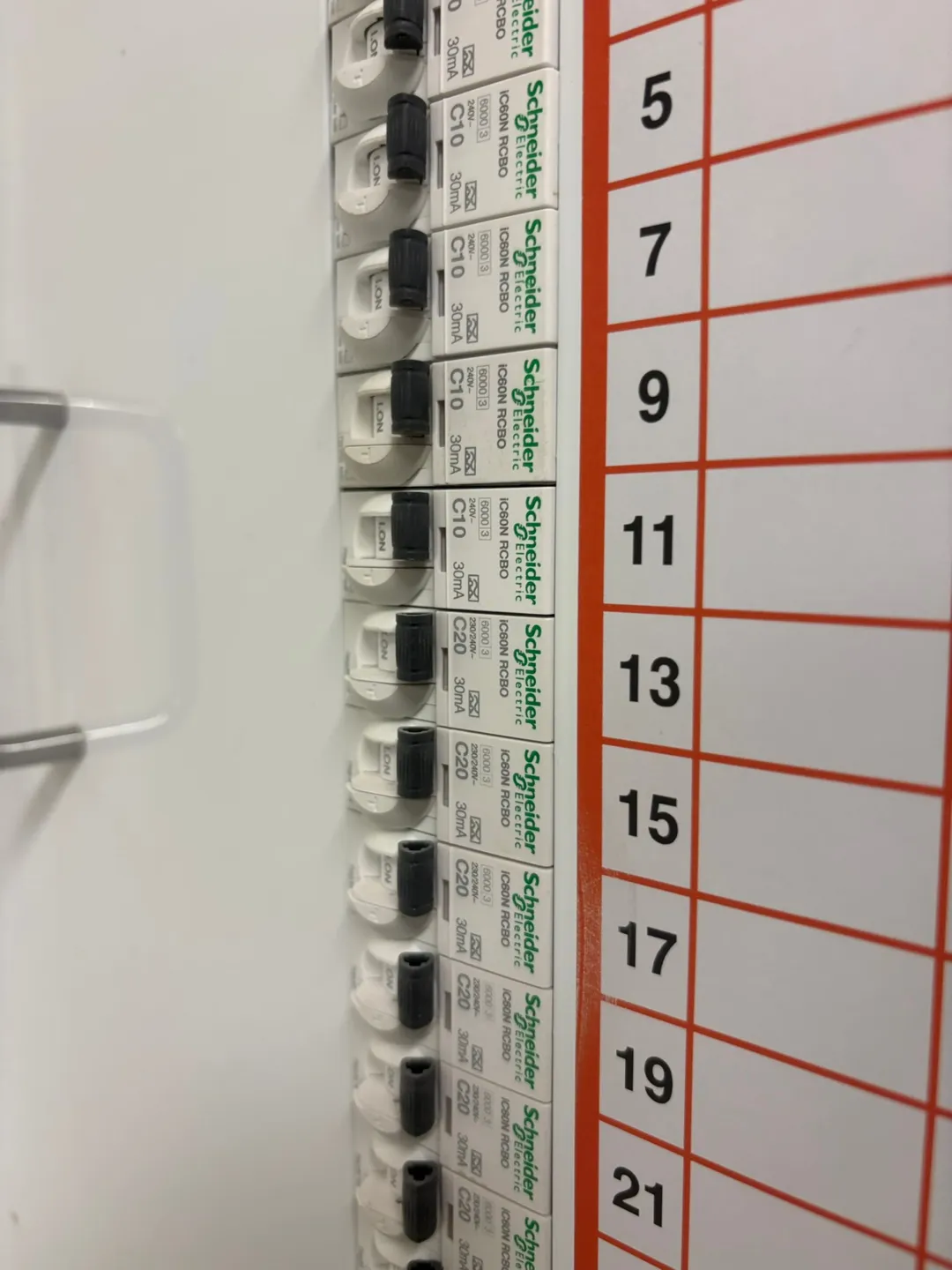 Row of 30mA RCBO safety switches in a commercial switchboard beside a numbered circuit chart